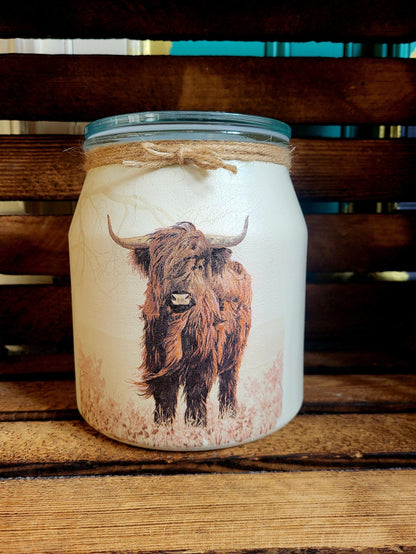 Candle in a jar with a bull design on a wooden surface