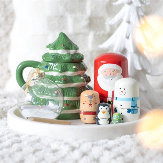 Set of Christmas-themed ceramic items including a tree-shaped teapot and Santa Claus figurine on a white surface.